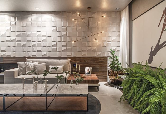 A Sala da Suíte Master, projetada por Simone Pedreschi, traz o piso em concreto combinado com as grandes peças de porcelanato nas paredes, que trazem um ar contemporâneo para o ambiente. O verde é impresso através de vasos com diferentes espécies de plantas, como a samambaia.