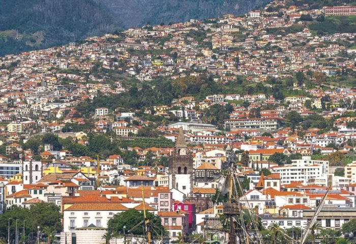 A vista do oceano para a capital da Ilha de Madeira, Funchal, e um dos barcos que fazem os passeios entre as ilhas do arquipélago.