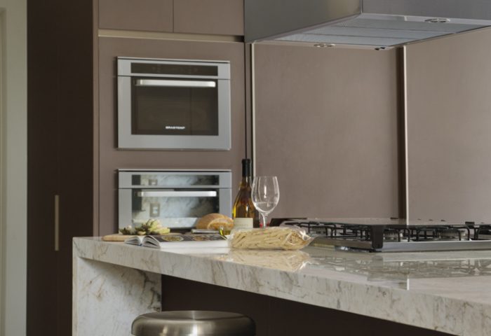 Clean e moderna, a cozinha é composta por bancada em mármore Calacata Paraná (Stone Center e execução da Granitex), armários feitos sob medida (Kitchens), coifa (Refrigeração Araçatuba) e banquetas em inox. No piso, pastilha cestavada da Ornamentare
