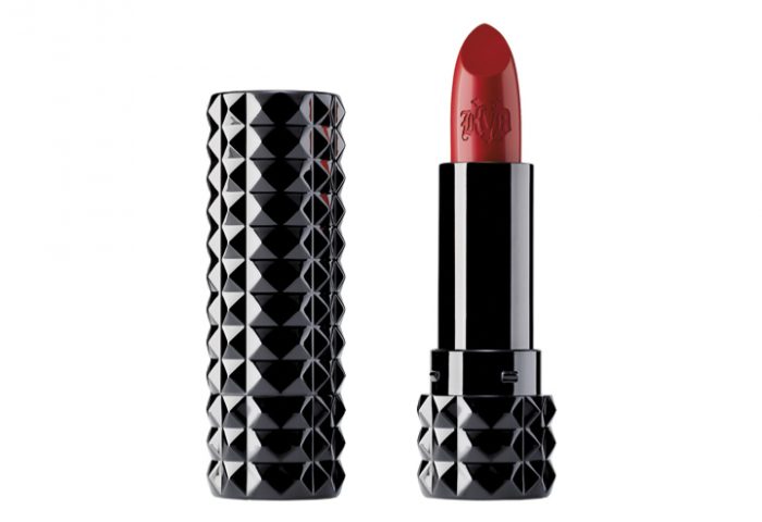 Da Kat Von D, o batom Studded Kiss na cor Adora é um vermelho médio escuro com tons quentes e um brilho metálico vermelho rubi sobre um acabamento fosco