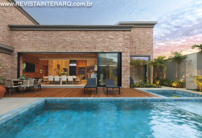 João Fávero e Ana Cláudia Ribeiro Angelo uniram a área interna e externa visualmente graças à grande abertura das esquadrias de alumínio (LA Esquadrias). A piscina revestida em porcelanato Pacific da Portinari (Casa dos Construtores) conta com deck em madeira e o gourmet convida a momentos descontraídos