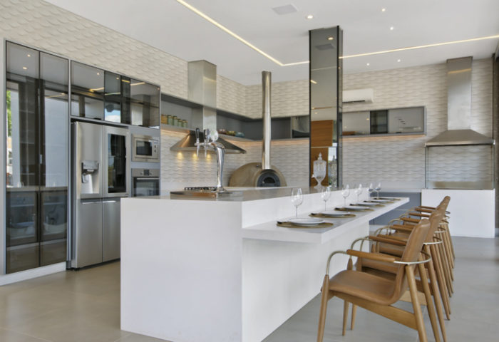 Eric Delcole e Tatiane Paulino desenvolveram, para esta casa à beira do rio, um espaço de convívio social totalmente integrado e conectado à área de lazer externa por grandes panos de vidro. A área gourmet conta com churrasqueira, forno à lenha, chopeira e muito mais para reuniões de família e amigos